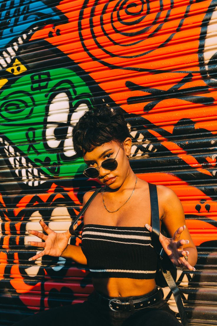 a woman standing in front of a graffiti wall