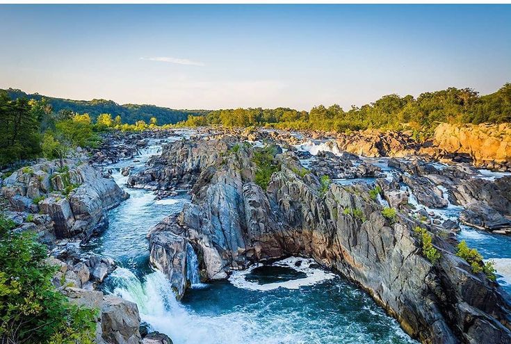 an aerial view of a river flowing between two large rocks with trees on the other side