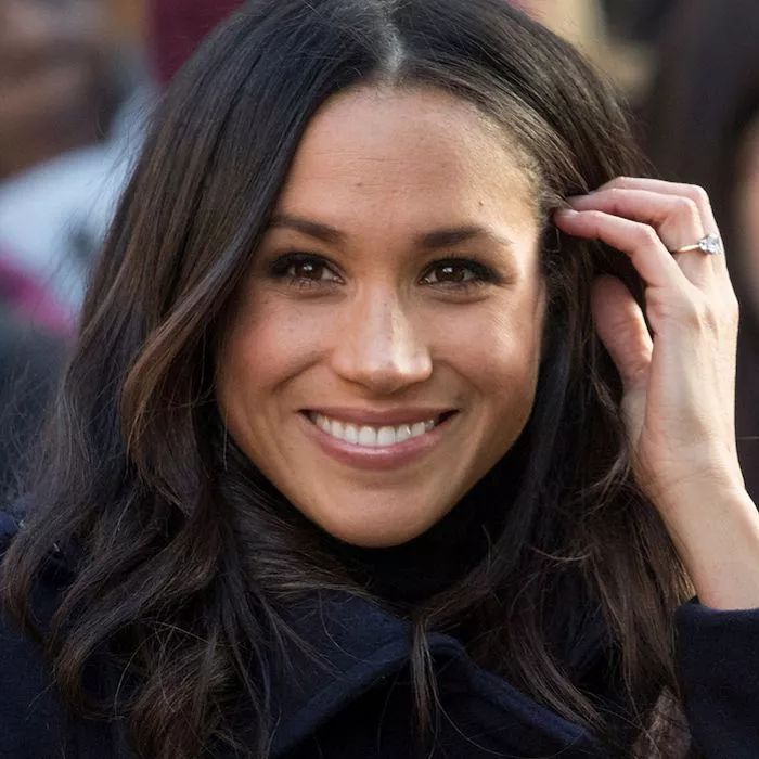 a close up of a person wearing a ring and smiling at the camera with people in the background