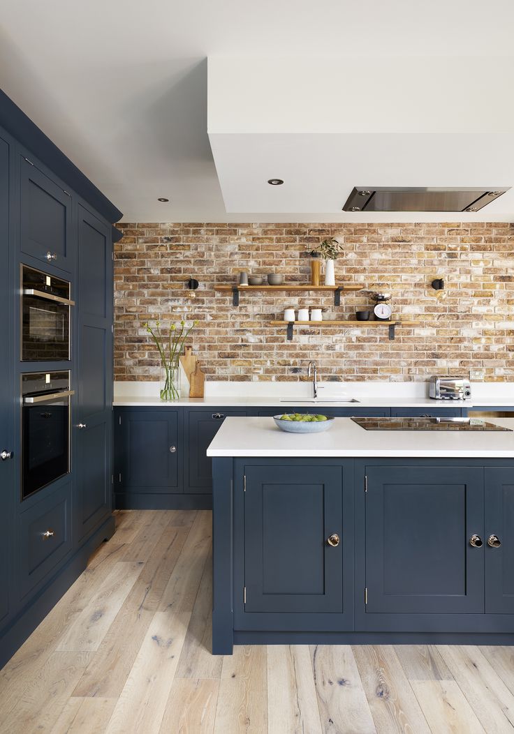 a large kitchen with blue cabinets and white counter tops, along with wooden flooring