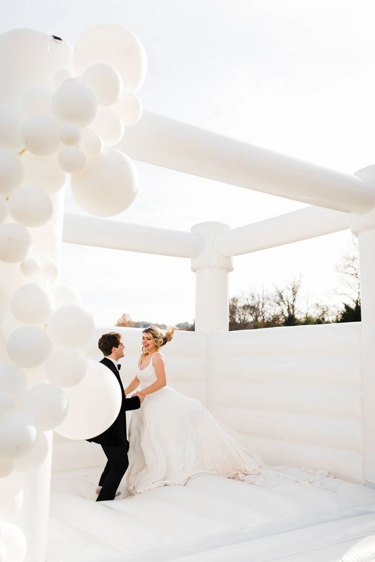 a bride and groom standing in front of white balloons