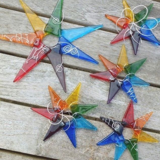 six colorful glass star ornaments sitting on top of a wooden table