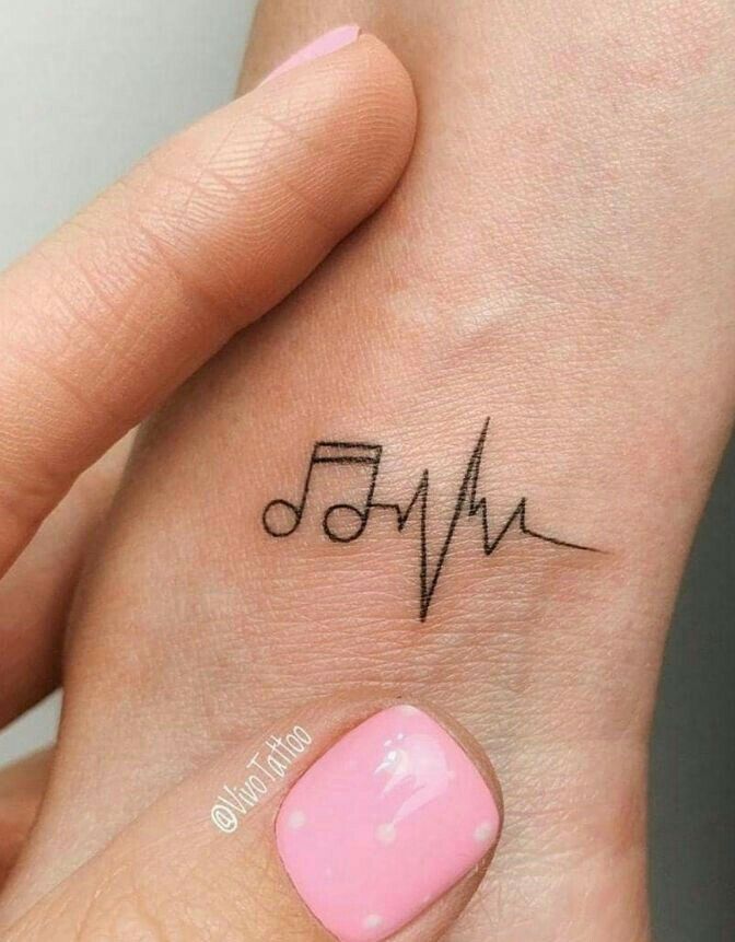 a woman's hand with a small heartbeat tattoo on her left wrist and the word music written in black ink