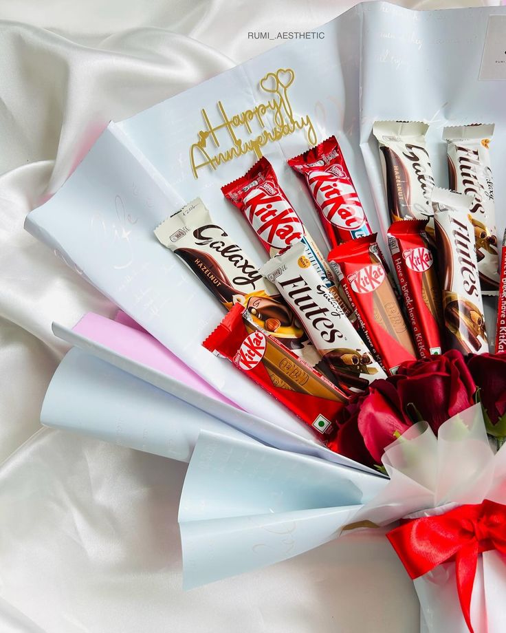 a bunch of candy wrapped in paper on top of a white sheet with a red bow