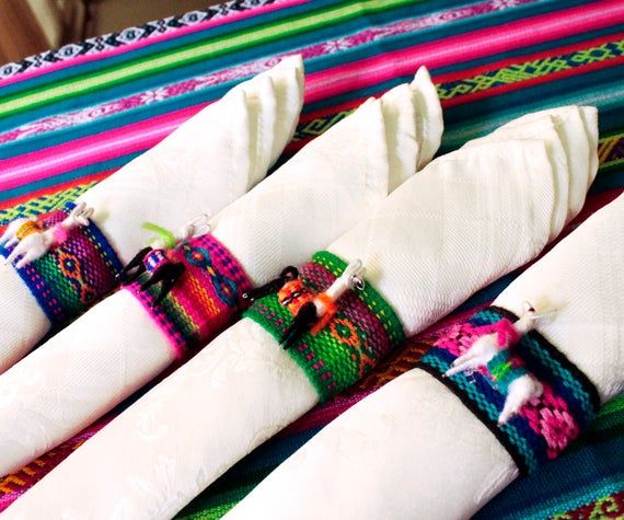 four white napkins are lined up on a colorful table cloth