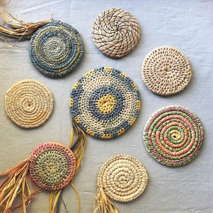 several woven coasters are arranged on a white tablecloth, with some tassels in the middle