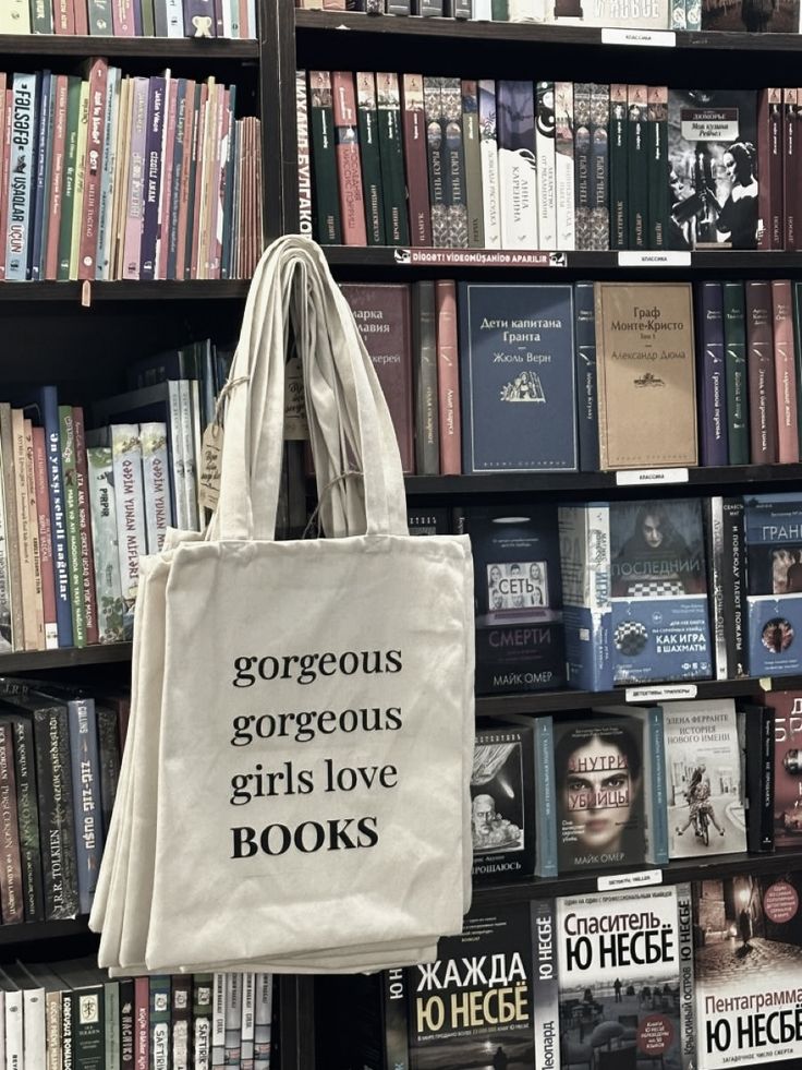 a book shelf filled with lots of books and a tote bag hanging from it