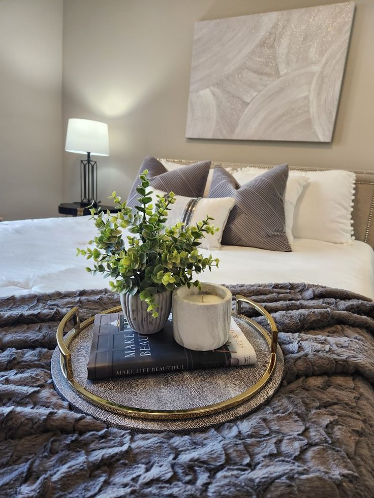 a tray with a plant on top of it in front of a bed and pillows