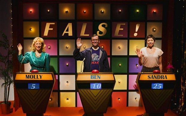 three people standing on stage with their hands up in front of the screen that says false