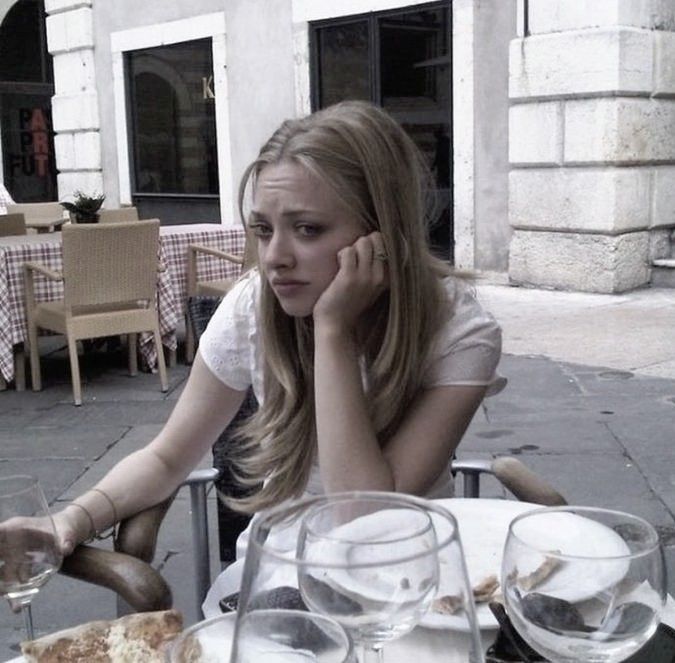 a woman sitting at a table with wine glasses