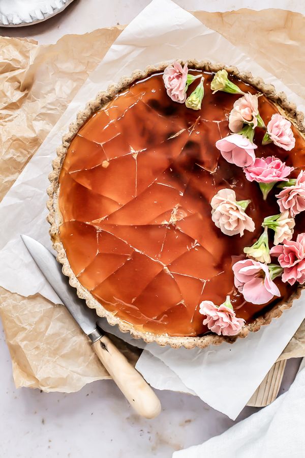 a close up of a pie with flowers on it and text overlay that reads, ear grey creme brule tart lightly infused with bergamot