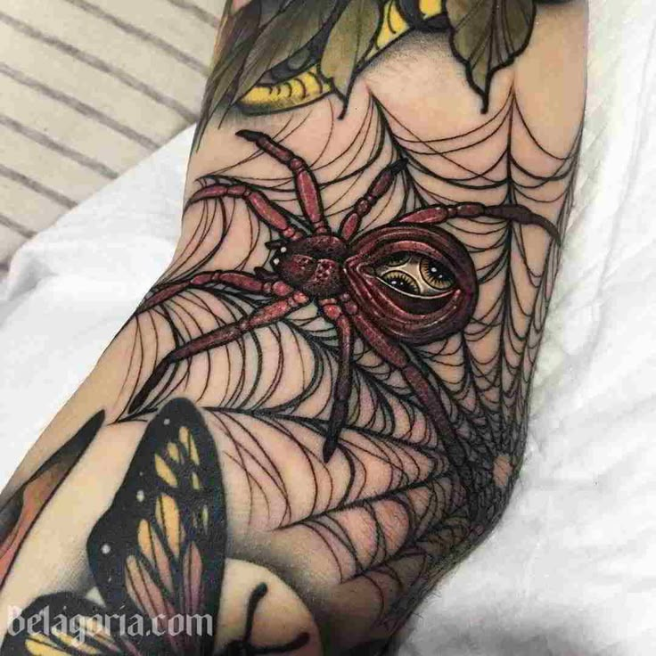 a person with a spider web tattoo on their arm and leg, holding a butterfly