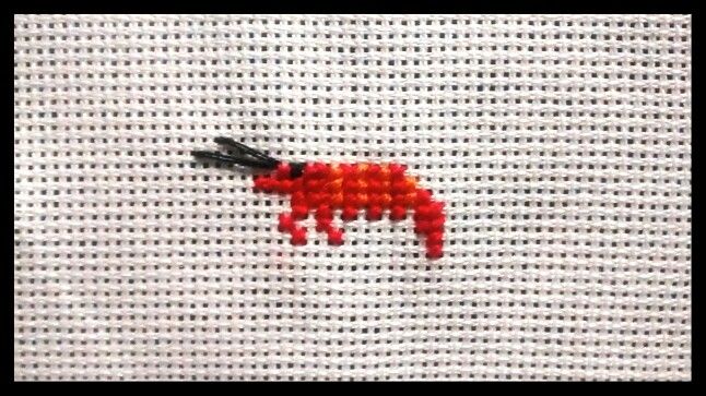 a needle is hooked up to the side of a piece of fabric with red beads on it