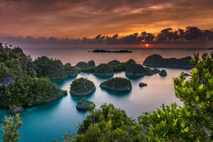 the sun is setting over an island with many small rocks and trees on it, as seen from above