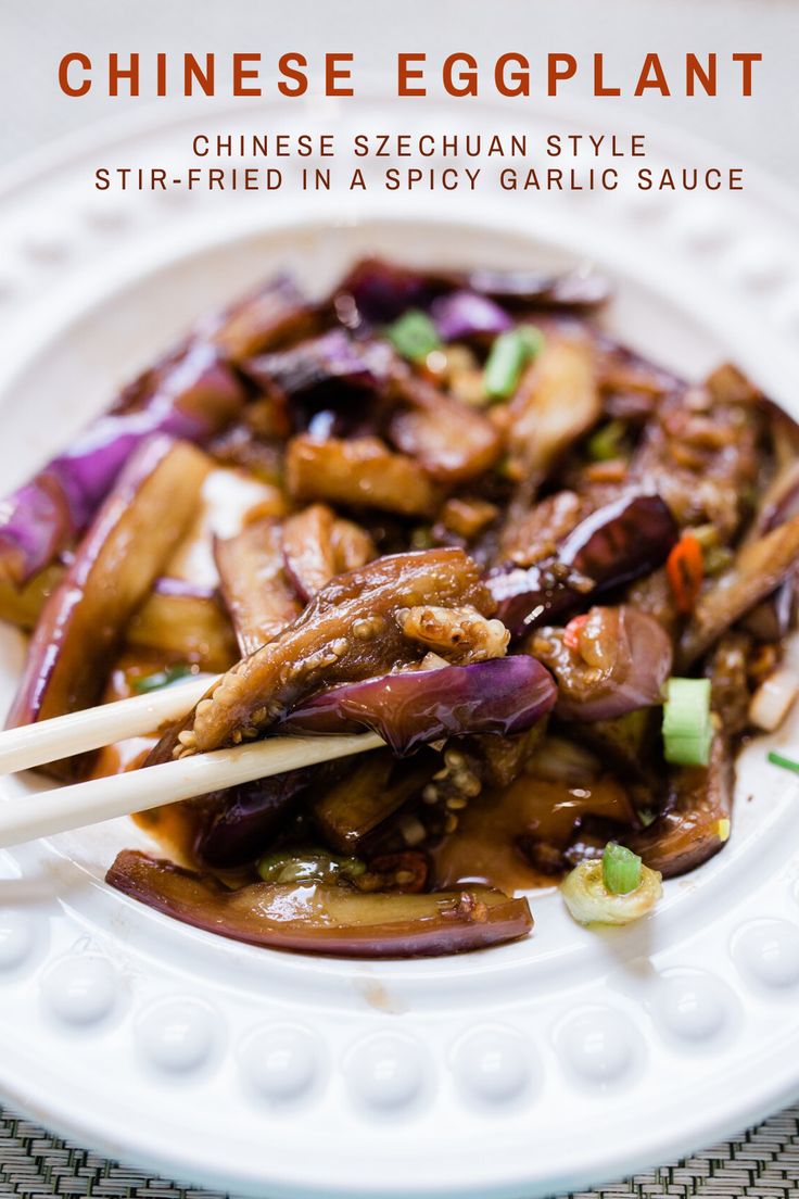 chinese eggplant stir fried in a spicy garlic sauce with chopsticks on a white plate