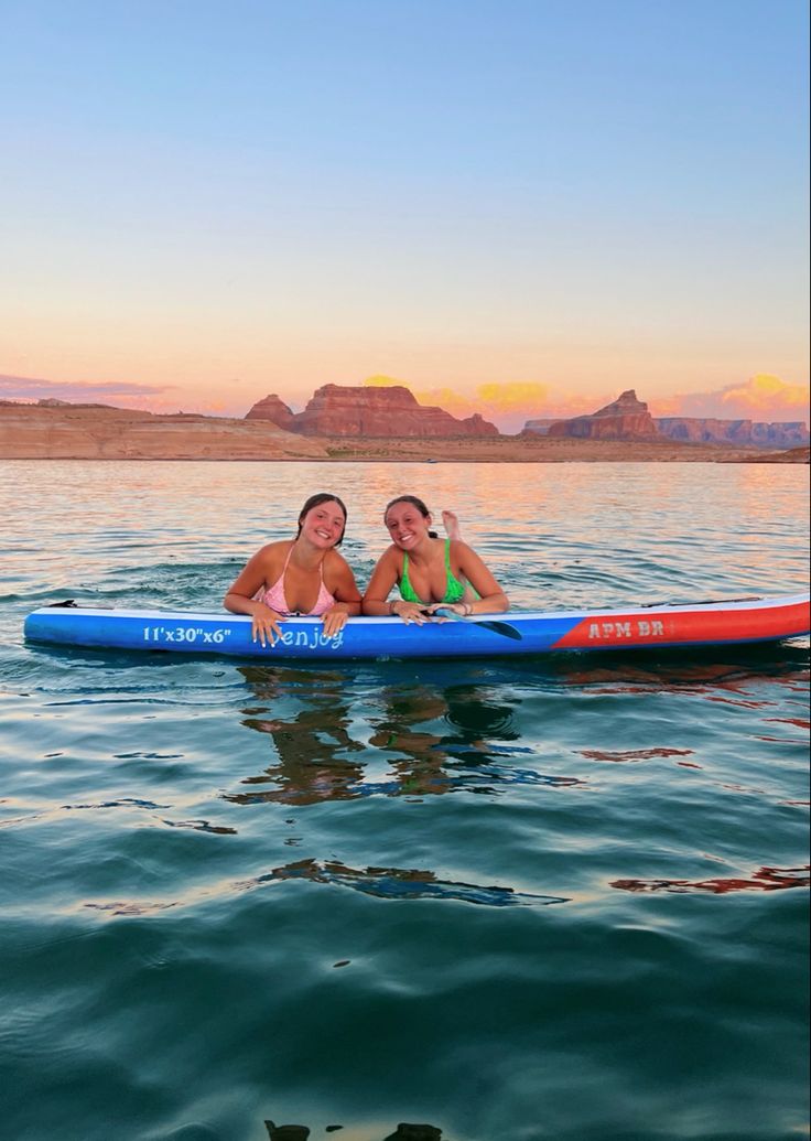 two women are sitting on a paddle boat in the water