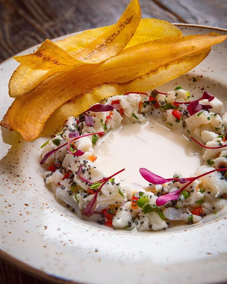 a white plate topped with food next to a pile of potato wedges on top of a wooden table