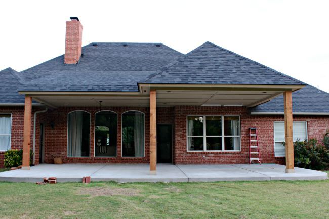 a red brick house with a covered porch and large grass area next to the front door