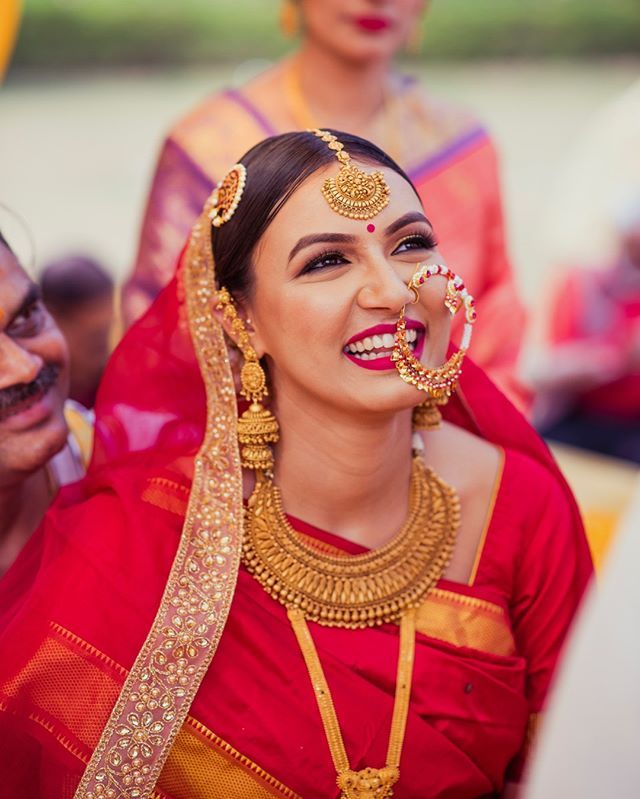 a woman in a red sari smiles as she stands with other people behind her