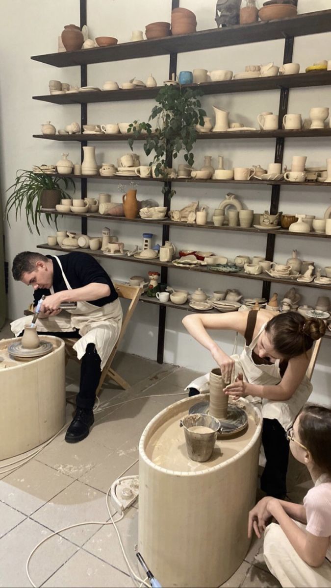 three people working on pottery in a shop