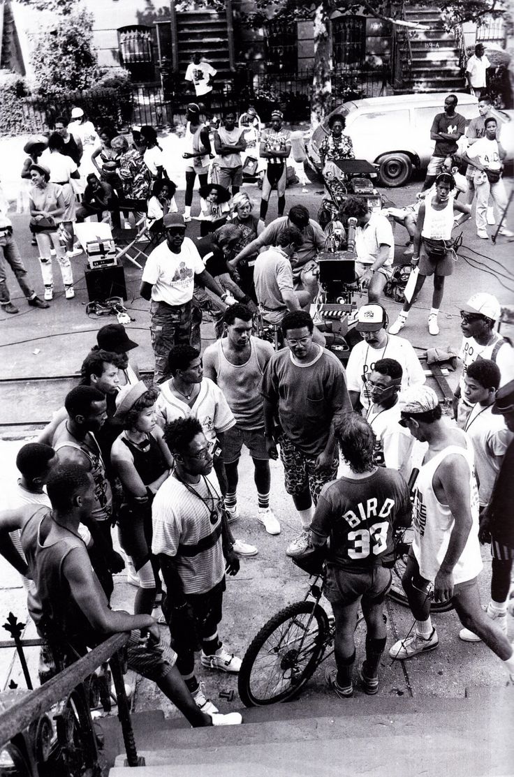 a group of people standing around each other in front of a crowd on the street