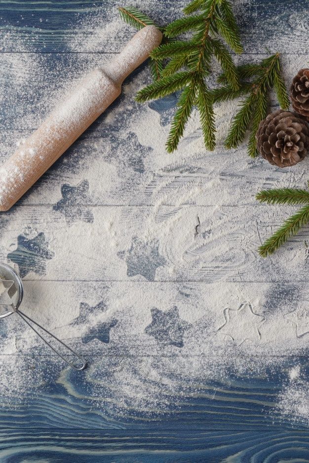 some pine cones are next to a rolling pin on a wooden table with snow and fir branches