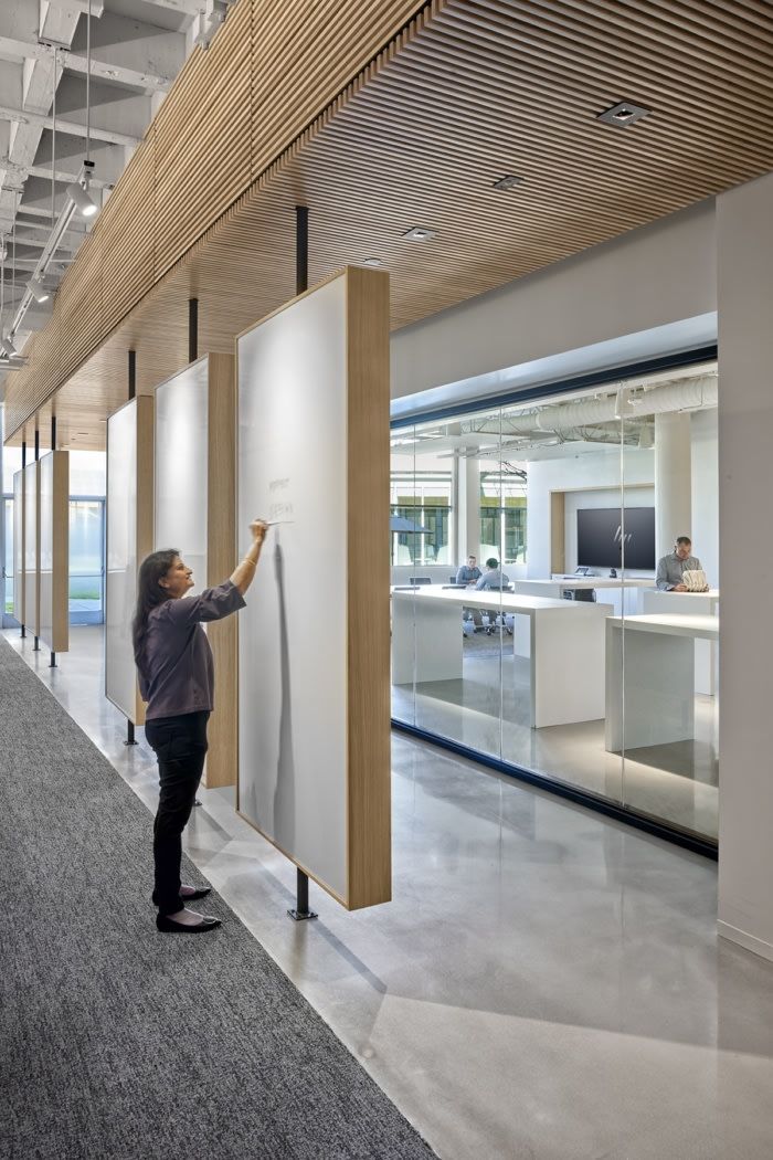 a person standing next to a white board in an office building with lots of windows