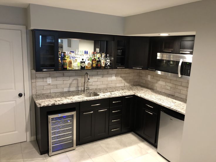 an empty kitchen with black cabinets and white marble counter tops is seen in this image