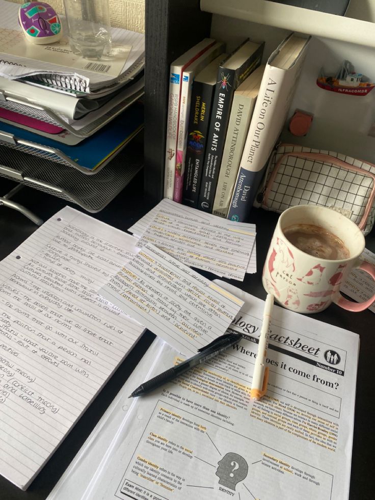 a cup of coffee sitting on top of a desk next to some books and papers