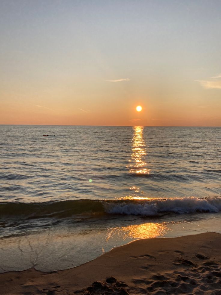 the sun is setting over the water at the beach