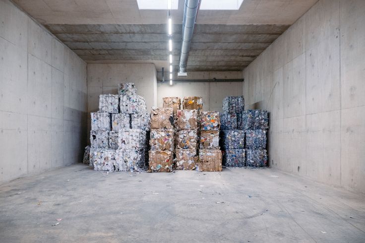 there are many stacks of boxes in the room with concrete walls and beams on the ceiling