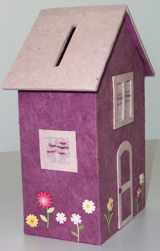 a paper doll house with flowers painted on the front and side walls, sitting on a table