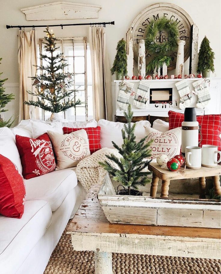 the living room is decorated for christmas with red and white pillows, pine trees, and other holiday decorations