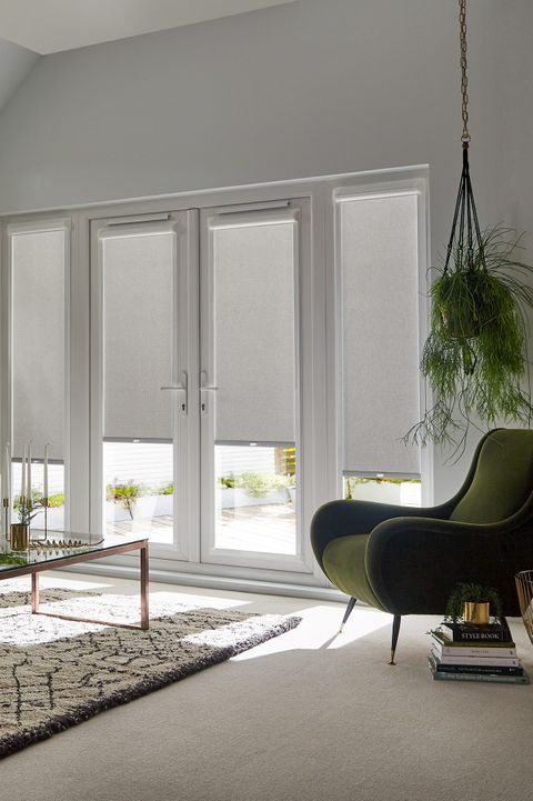 a living room filled with furniture and windows covered in white roller shade shades on the sliding glass doors