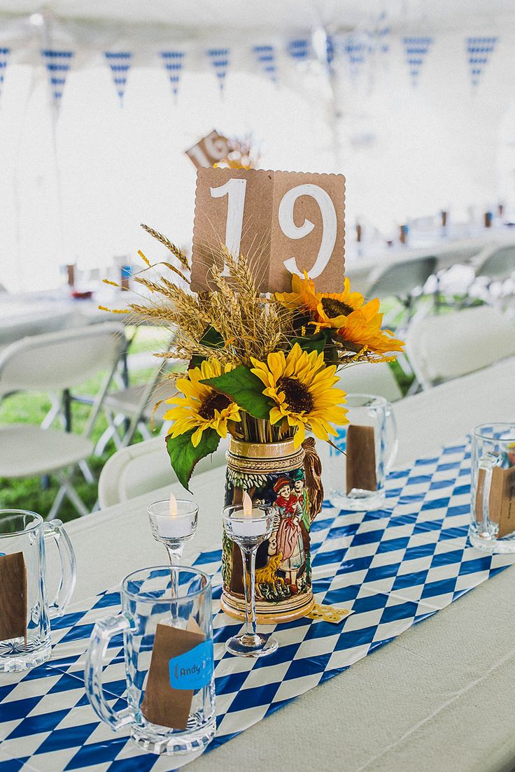 a vase with sunflowers and other flowers on a blue and white table cloth