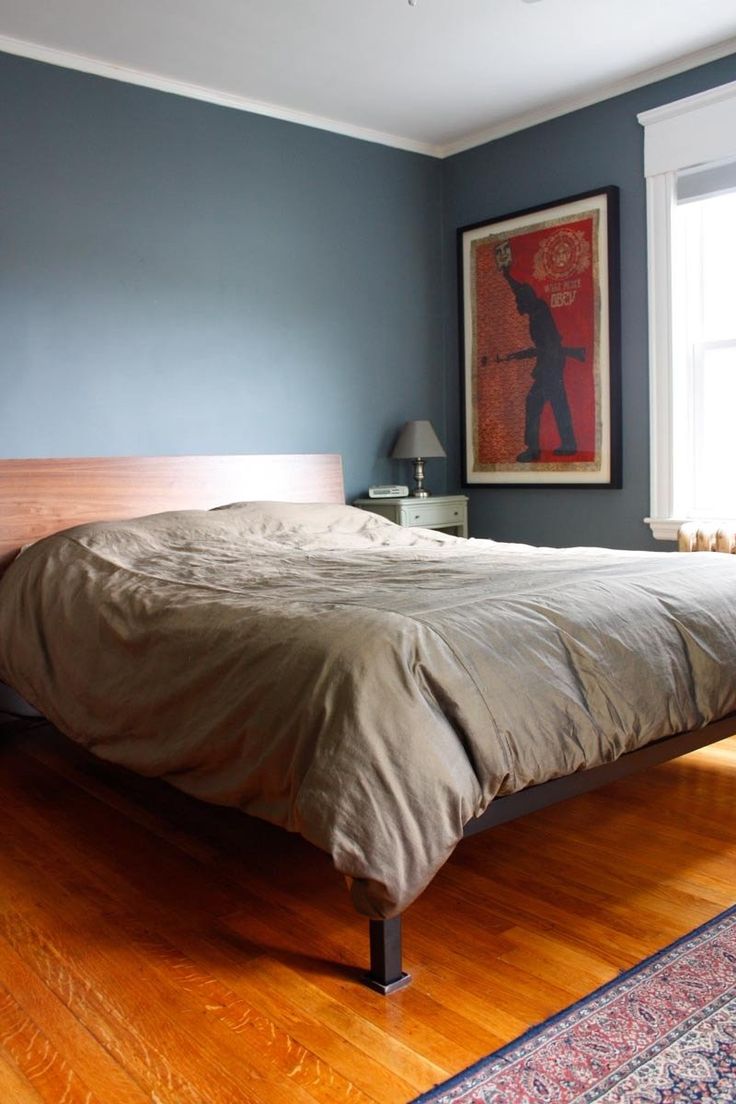 a bed sitting on top of a hard wood floor next to a window in a bedroom