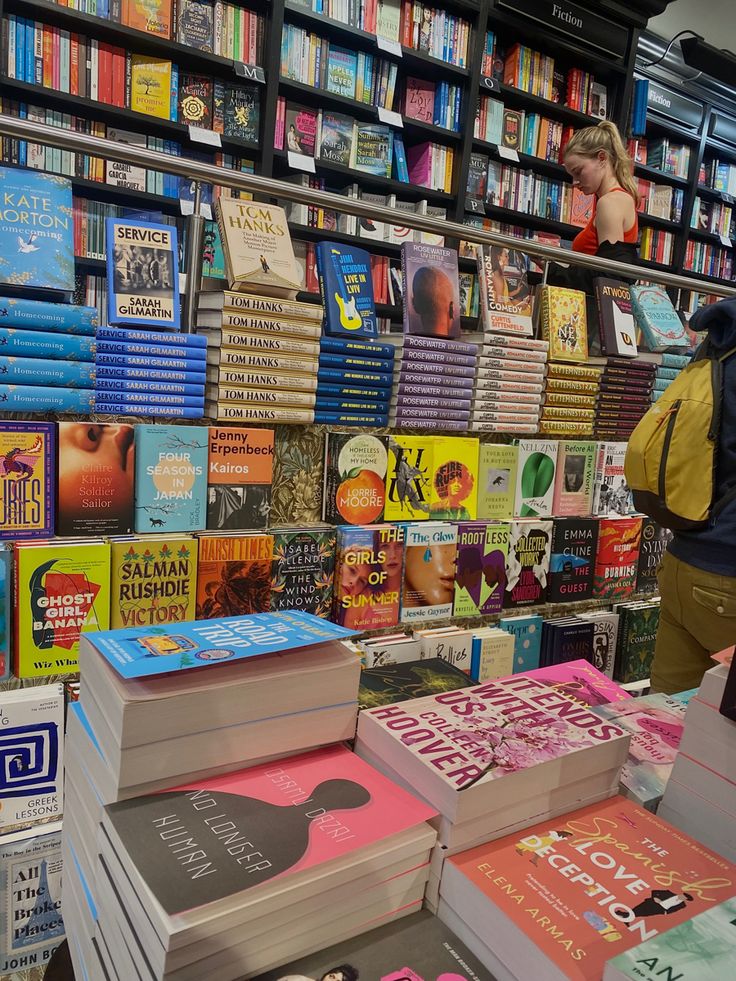 there are many books on display in the store and one person is looking at them