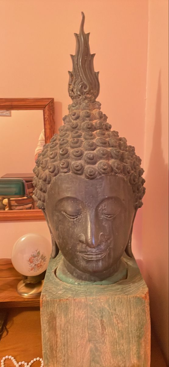 a buddha statue sitting on top of a wooden table next to a mirror and other items