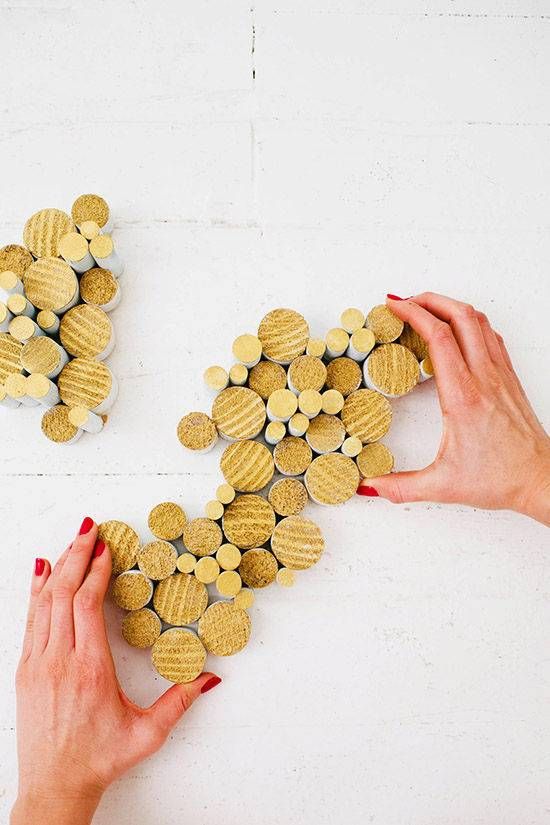 two hands are holding small gold hearts on a white surface