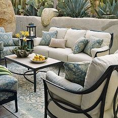 a living room filled with lots of furniture next to a stone wall and potted plants