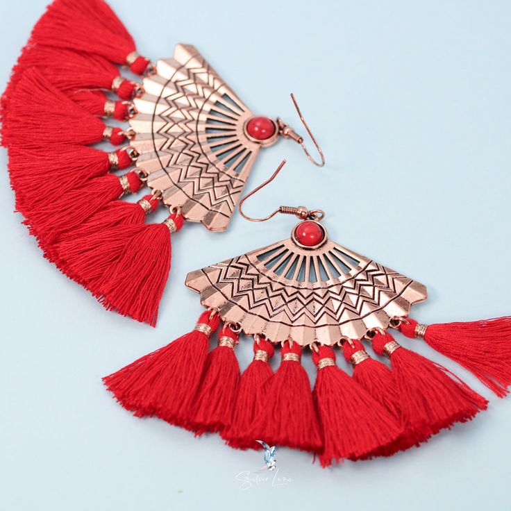 These unique bohemian fan tassel earrings feature red fan tassel on metal fan charm. Add these unique boho fan tassel dangle drop statement earrings to your everyday fashion earrings collection or as gift for your love one. Materials: mettal, cotton tasselFinish: rose gold color Jewelry Care: See more information about how to care for your jewelry here. Shipping Policy: Orders will be shipped within 1-3 business days. Economy shipping will take 7-14 days to arrive and standard shipping is 1- 4 d Red Metal Earrings For Summer, Red Dangle Tassel Earrings With Latkans, Red Bohemian Tassel Earrings As Gift, Metal Tassel Fringe Drop Earrings, Bohemian Metal Tassel Earrings With Fringe, Bohemian Metal Chandelier Earrings With Tassels, Elegant Red Tassel Earrings For Summer, Red Bohemian Metal Chandelier Earrings, Bohemian Red Metal Chandelier Earrings