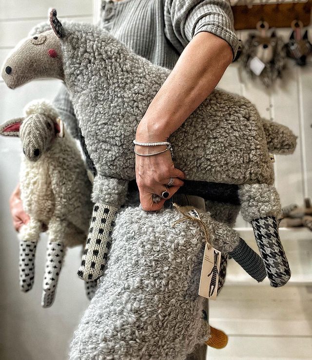 a person holding two stuffed animals in their hands, one is gray and the other is black