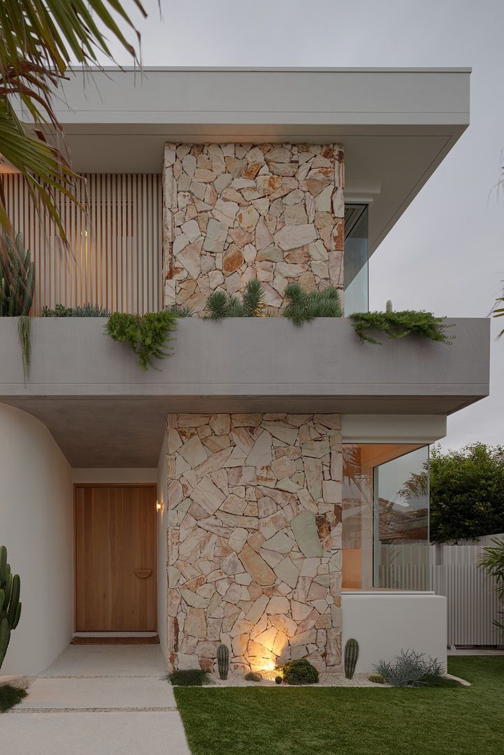 a modern house with stone facade and plants on the balconies