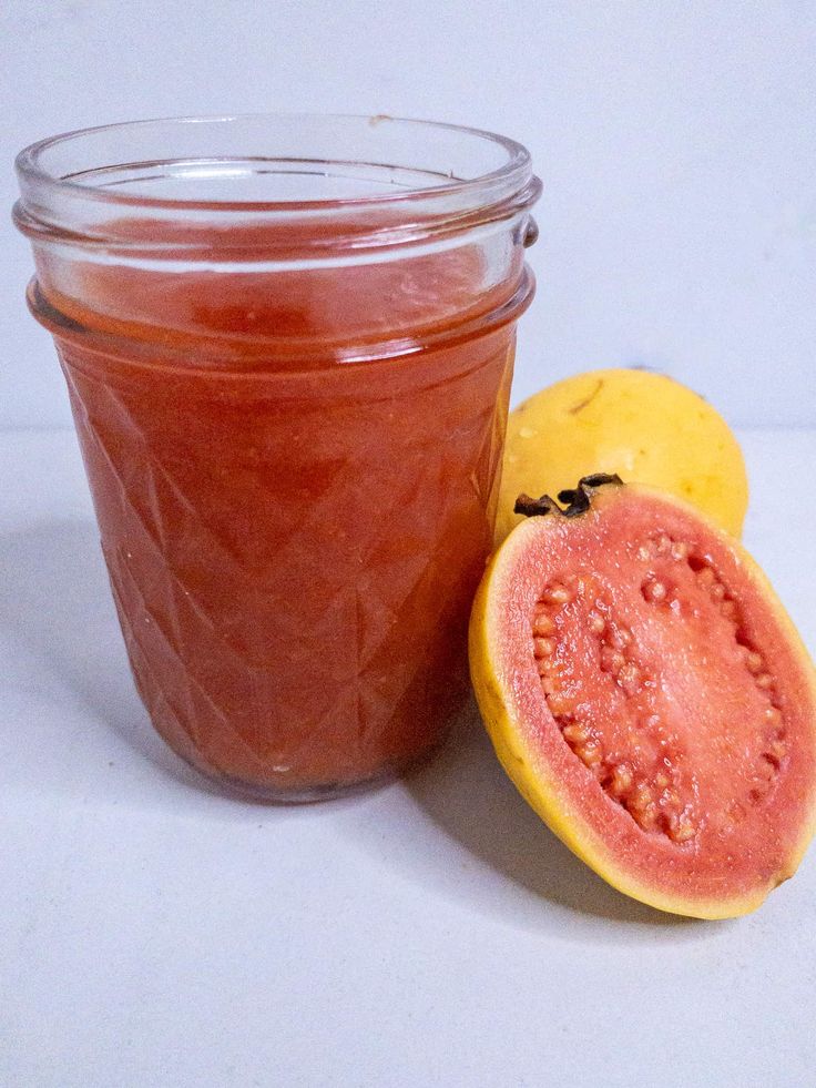 a glass jar filled with jam next to a half - eaten melon