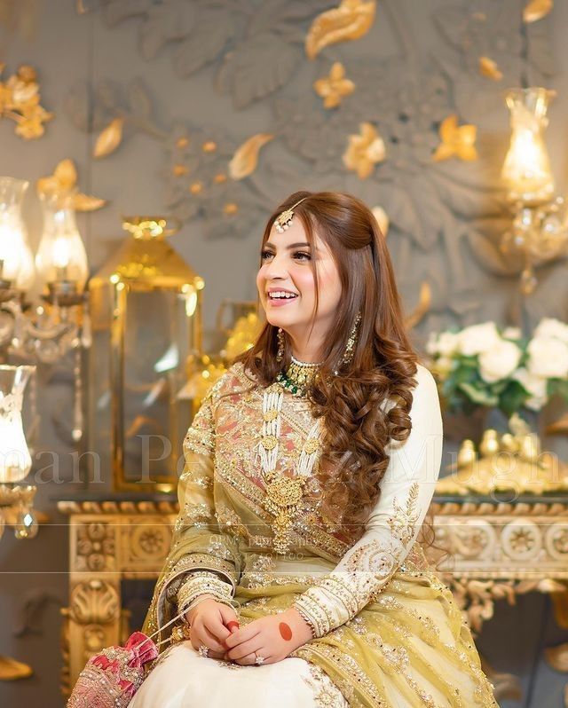 a woman sitting on top of a chair in a room filled with gold and white decorations