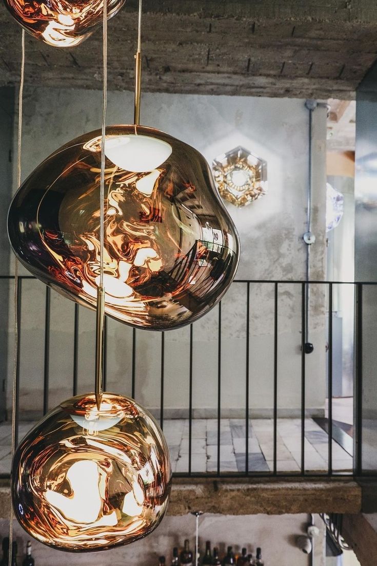 three lights hanging from the ceiling in a room with metal railings and chandeliers