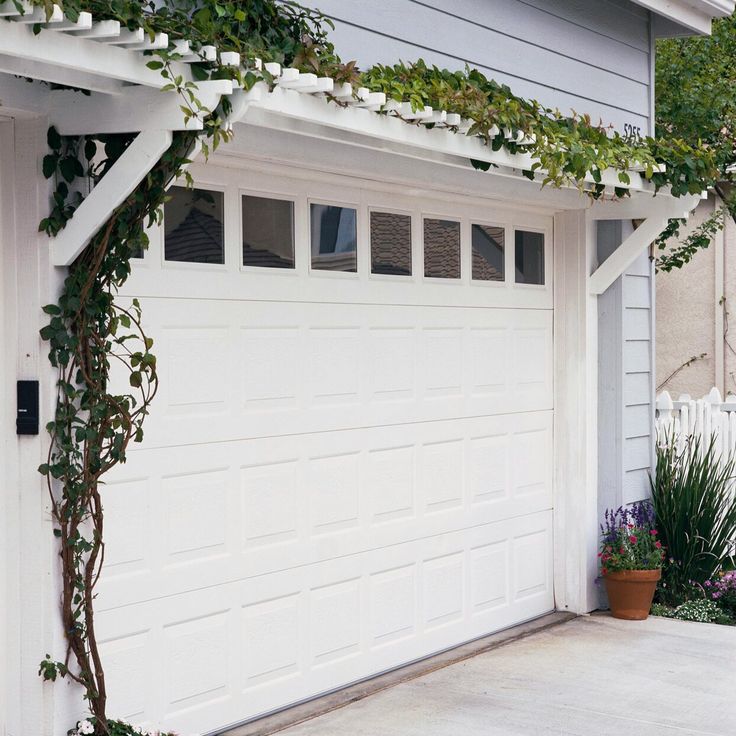 a white garage with plants growing on the side