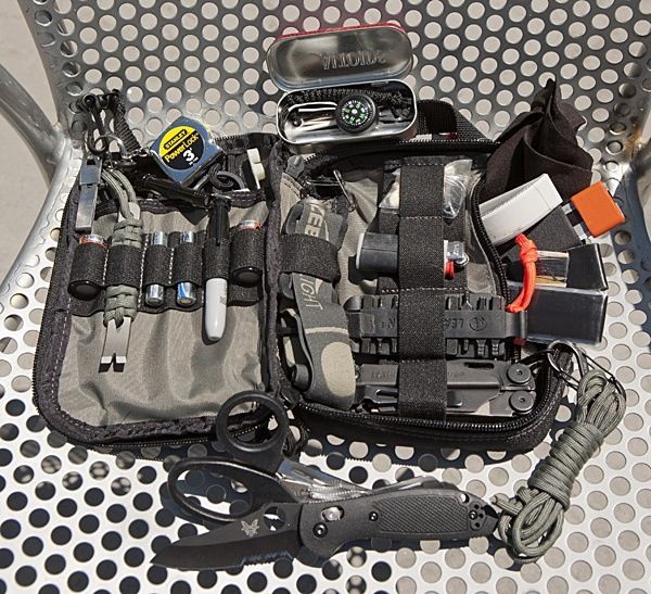 the contents of a tool bag sitting on top of a metal table next to scissors and other items