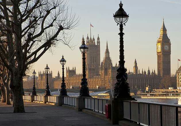 the big ben clock tower towering over the city of london from across the river thames