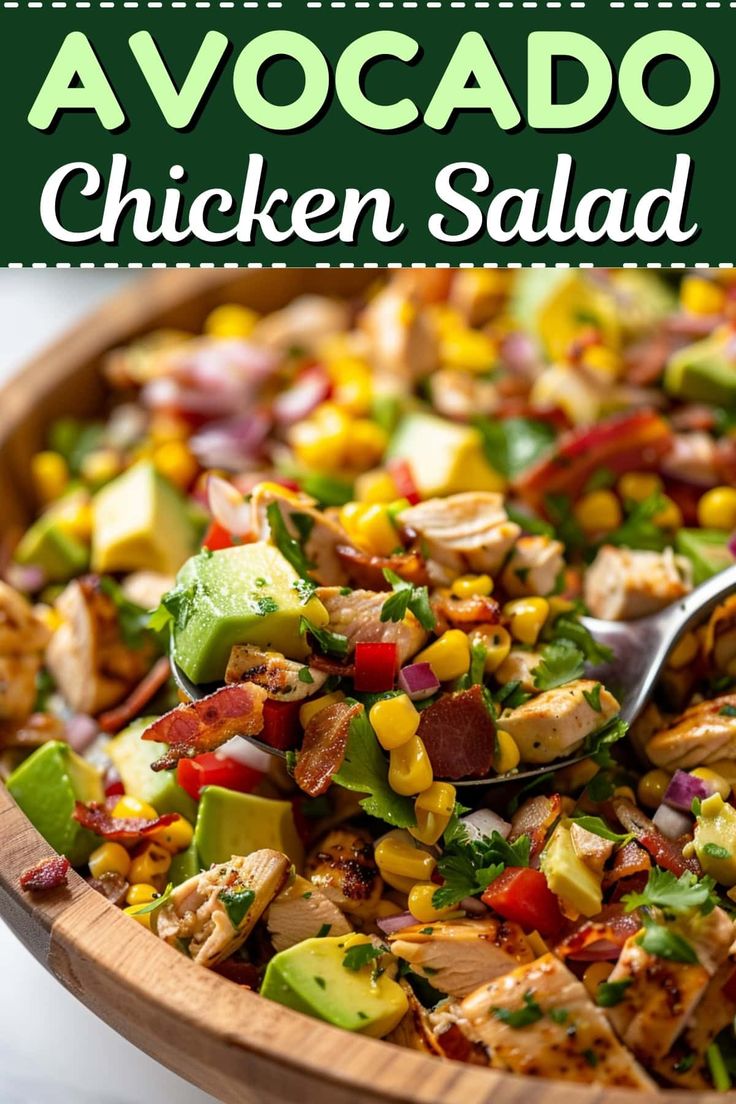 a salad with chicken, avocado and corn in a wooden bowl